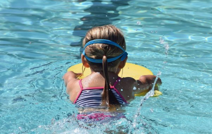 dziewczynka pływająca w basenie z żółtą deską