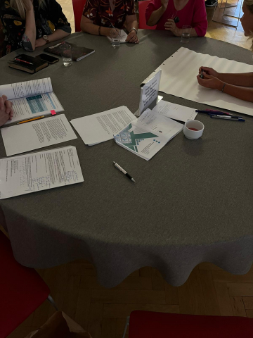 zdjęcie stołui nakrytego ciemnym obrusem z rozłożonymi dokumentami