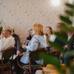 Osoby siedzące na krzesłach i patrzące się do przodu